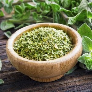 Fresh and dried oregano herb on wooden background